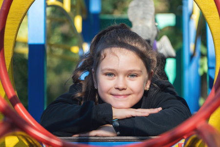 Cute beautiful smiling little girl on playground on sunny day.の写真素材