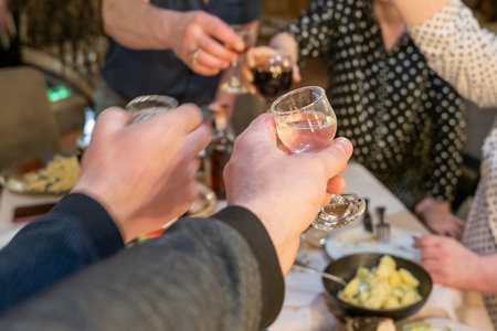 A group of friends click glasses of alcohol as they celebrate the holiday at a festive table.