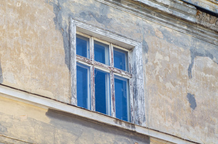Old wooden window with peeling paint in the wall of an old building.の写真素材