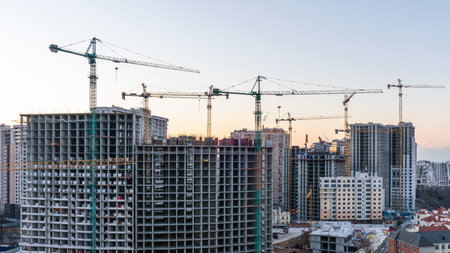 Construction site, cranes and multi-storey unfinished buildings at sunrise or sunset.の写真素材