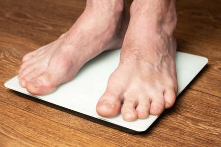A man measures his weight by standing on a floor scale.の写真素材