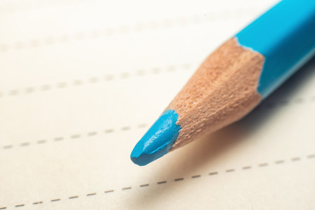 The point of a blue pencil touching a piece of paper with a dotted line, close-up macro shot.の写真素材
