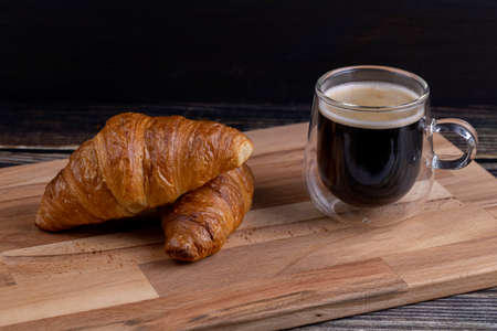 Croissants with a cup of coffee on a wooden board.の写真素材