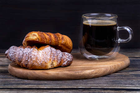 Sweet buns with a cup of coffee on a wooden board.の写真素材