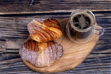 Sweet buns with a cup of coffee on a wooden board.の写真素材