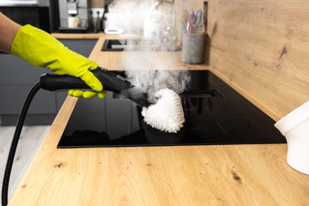 cropped view of woman in rubber glove cleaning induction cooker in kitchen