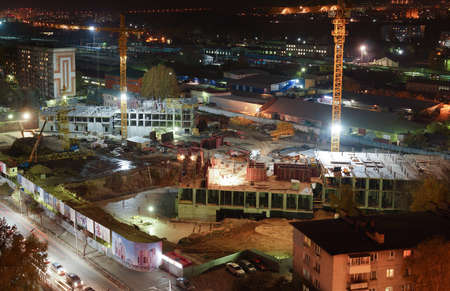 Night construction site with cranes, special equipment, lighting