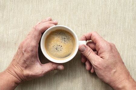 Men's hands hold a cup with coffee on a linen backgroundの写真素材
