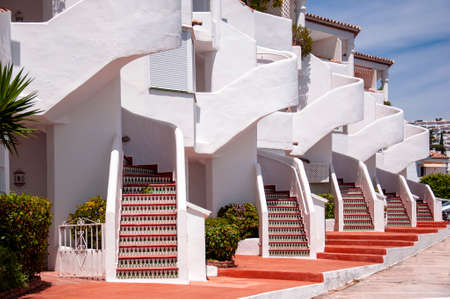 Block of several two-story white townhouses with colored stairs to the second floor and a red sidewalkのeditorial素材