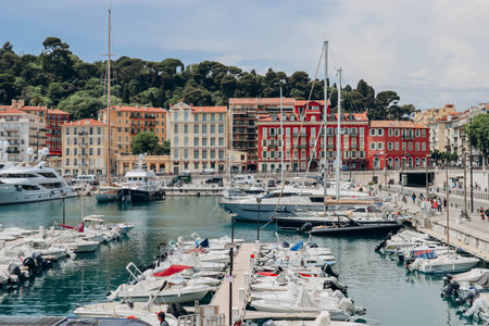 Nice, France - 01 June 2023: View of the port of Nice, moored yachts and boats, and the brightly colored facades of the surrounding housesのeditorial素材