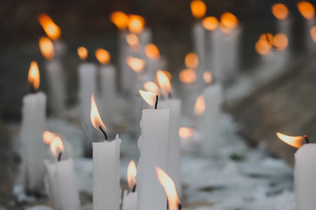 Close-up of lit white candles, partially out of focusの写真素材