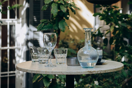 Glasses and a carafe with water on a table in the gardenの写真素材