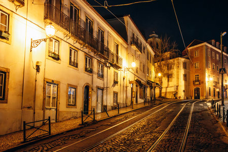 Picturesque streets of the Alfama district in Lisbon at night, illuminated by warm lightsの写真素材