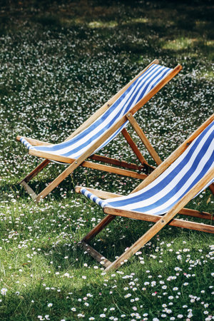 Two striped blue and white deck chairs on a lawn in the garden