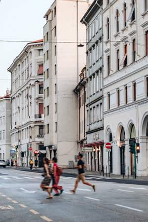 Trieste, Italy - August 18, 2024: Three people crossing the street in the city center of Trieste, with urban traffic in the backgroundのeditorial素材