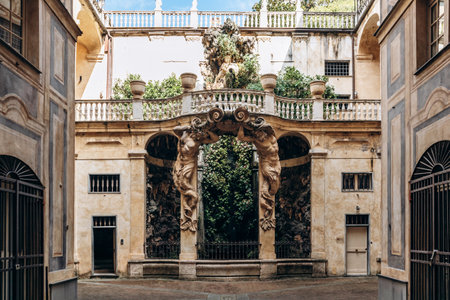 Genoa, Italy - September 22, 2024: Baroque courtyard with monumental atlantes and lush grotto in...
