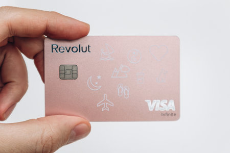 Paris, France - 23 February 2025: A hand holding a customized pink Revolut bank card, showcasing modern banking and digital payment services.のeditorial素材