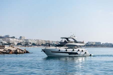 Cannes, France - March 8, 2025: Luxury yacht cruising on the sea with cityscape in the background.