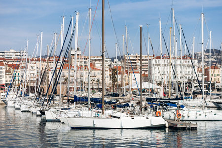 Cannes, France - March 8, 2025: Fishing boats and yachts in the Old Port with Palais des Festivals and city hills in the background.のeditorial素材