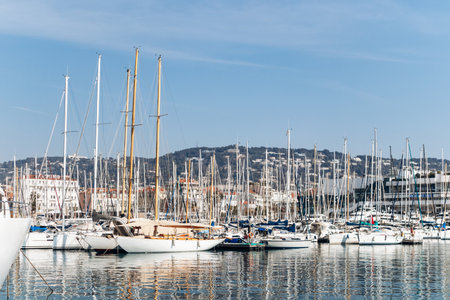 Cannes, France - March 8, 2025: Fishing boats and yachts in the Old Port with Palais des Festivals and city hills in the background.のeditorial素材