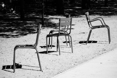 Iconic green metal chairs stand empty on a sunlit gravel path in the famous city park - Luxembourg Garden, Paris, Franceの写真素材