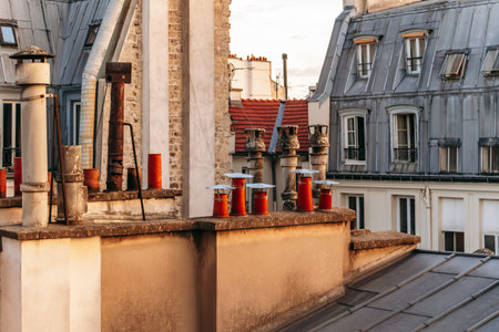 Classic Paris rooftops with chimneys and mansard windows at sunset.の写真素材