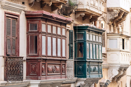 Traditional Maltese wooden balconies painted in vibrant colors on limestone facades, typical architecture of the historic city center.の写真素材