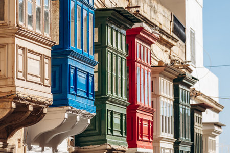 Traditional Maltese wooden balconies painted in vibrant colors on limestone facades, typical architecture of the historic city center.の写真素材