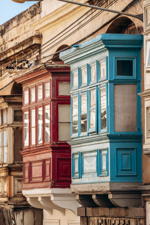 Traditional Maltese wooden balconies painted in vibrant colors on limestone facades, typical architecture of the historic city center.の写真素材
