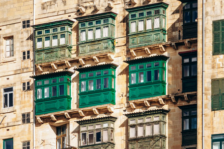 Traditional Maltese wooden balconies painted in vibrant colors on limestone facades, typical architecture of the historic city center.の写真素材