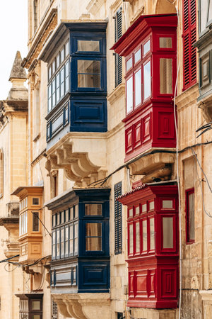 Traditional Maltese wooden balconies painted in vibrant colors on limestone facades, typical architecture of the historic city center.の写真素材