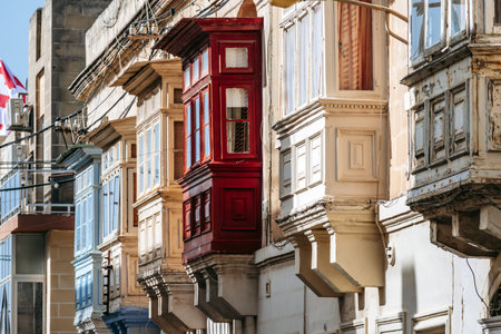 Traditional Maltese wooden balconies painted in vibrant colors on limestone facades, typical architecture of the historic city center.の写真素材