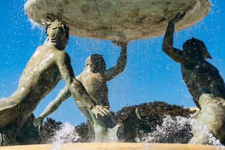 Tritonsâ Fountain at the entrance to Valletta, three bronze mythological sea gods supporting a large basin, with water jets sparkling under the clear Mediterranean skyの写真素材