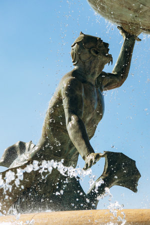 Tritonsâ Fountain at the entrance to Valletta, three bronze mythological sea gods supporting a large basin, with water jets sparkling under the clear Mediterranean skyの写真素材