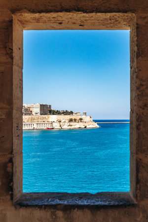 Scenic view of blue Mediterranean Sea and limestone fortifications framed through a window of the historic Senglea guard post at the tip of the peninsulaの写真素材