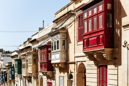 Traditional Maltese wooden balconies painted in vibrant colors on limestone facades, typical architecture of the historic city center.の写真素材