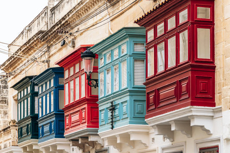 Traditional Maltese wooden balconies painted in vibrant colors on limestone facades, typical architecture of the historic city center.の写真素材