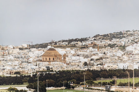 Distant view from Mdina over the cityscape of Mosta, with the iconic Rotunda of Mosta prominently rising above the white buildings.の写真素材