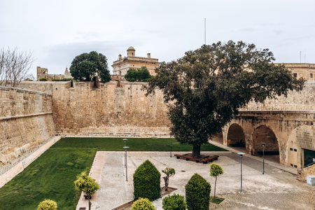 View of the historic fortified walls and gardens surrounding the ancient city of Mdina, with neatly...