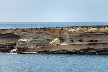Ras il-Fniek rocky headland with small coastal tower and layered limestone cliffs near the Munxar Windowの写真素材