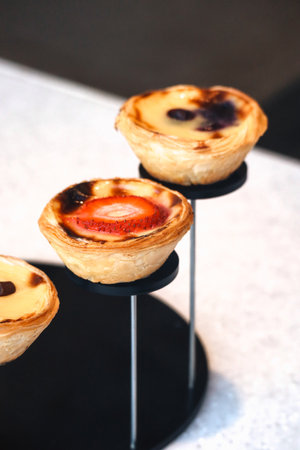 Portuguese pasteis de nata desserts dusted with powdered sugar, served on a black slate board.