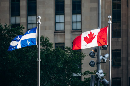 Montreal, Canada - August 11, 2025: Canadian and Quebec flags waving together in downtown Montreal, symbolizing unity and cultural identityの写真素材
