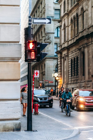 Montreal, Canada - August 11, 2025: Street scene in downtown Montreal with traffic light, cyclists, pedestrians and historic buildingsのeditorial素材