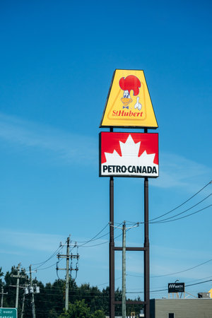 Trois Rivieres, Canada - August 15, 2025: Roadside sign with St Hubert logo above Petro Canada logo on blue sky backgroundのeditorial素材