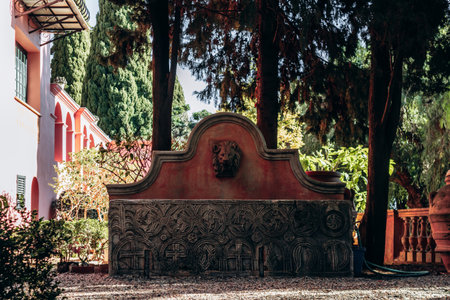 Roquebrune Cap Martin, France - February 9, 2025: Historic stone fountain with carved reliefs in a garden courtyard in the old village of Roquebrune Cap Martinのeditorial素材