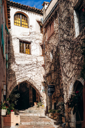 Roquebrune Cap Martin, France - February 9, 2025: Stone archway and narrow passage in the old town of Roquebrune with a person walking upstairsのeditorial素材
