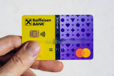 Nice, France - December 9, 2025: Close-up of Raiffeisen Bank debit card with Mastercard logo held in a male hand against a dark backgroundのeditorial素材