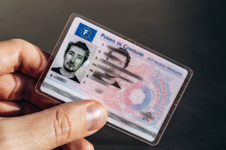Nice, France - December 9, 2025: French driving license held in a male hand, close-up view of official identification documentのeditorial素材