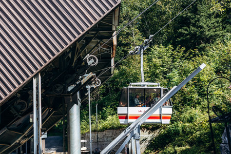 Chambord, Canada - August 18, 2025: White and red aerial tram car hanging from cables against forest at Val-Jalbert Historical Village in Quebecのeditorial素材