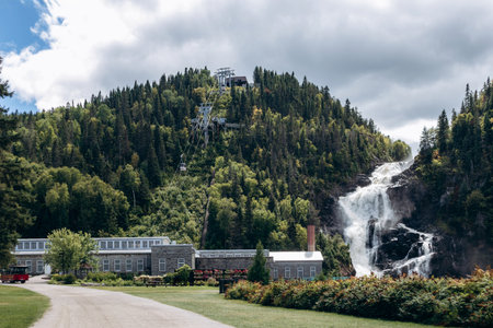Chambord, Canada - August 18, 2025: Ouiatchouan Falls with old stone mill buildings and aerial...